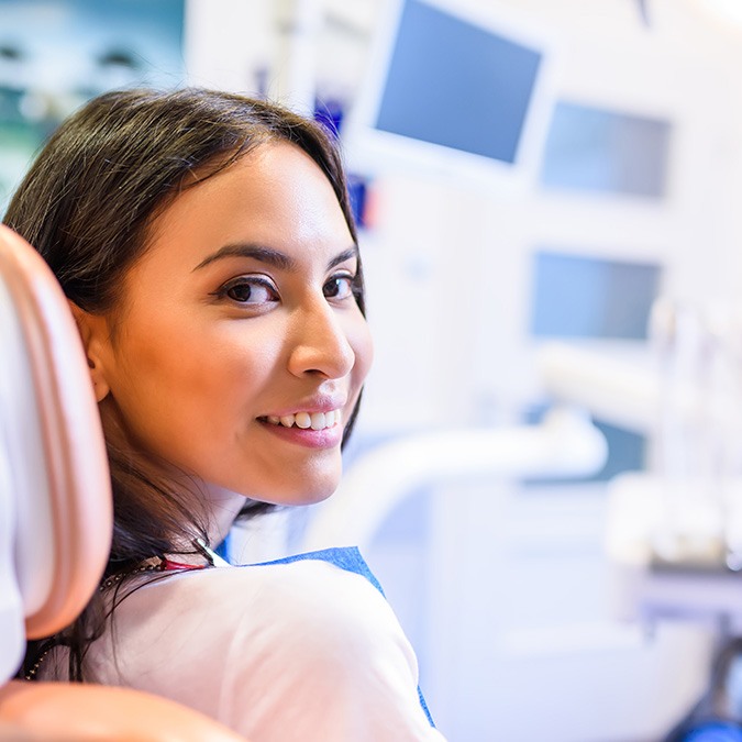 Woman in dental chair looking back and smiling