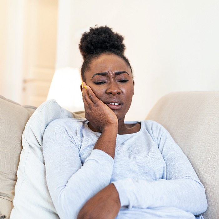 Woman with toothache sitting on couch at home