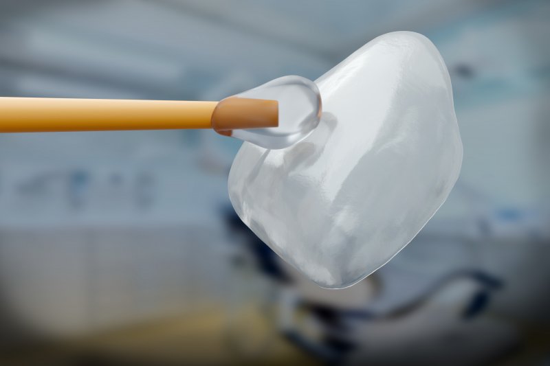 A closeup of a dental veneer with an applicator